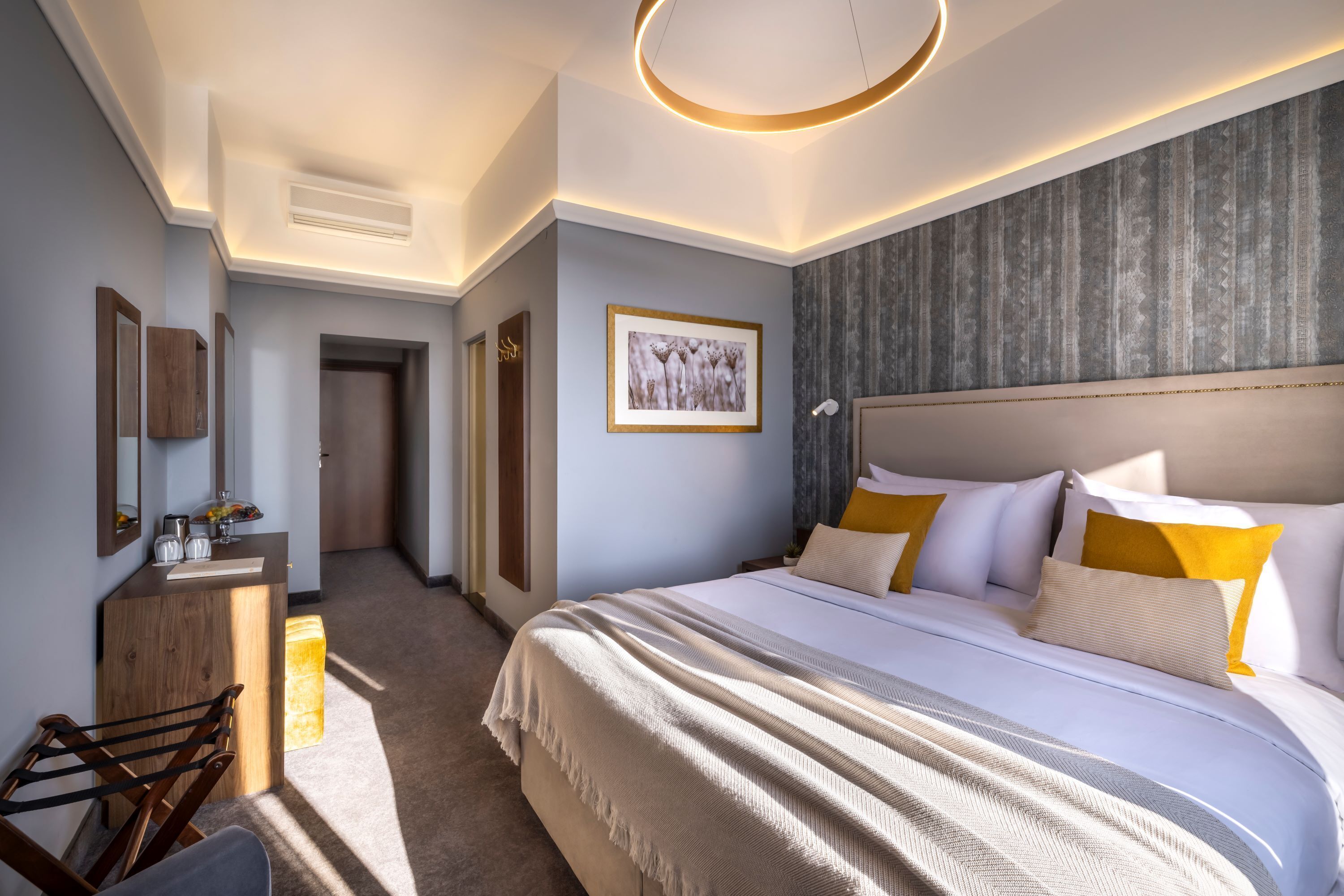 Ein modernes Hotelzimmer mit einem großen Bett, einem Holztisch und einem gerahmten Bild an der Wand.