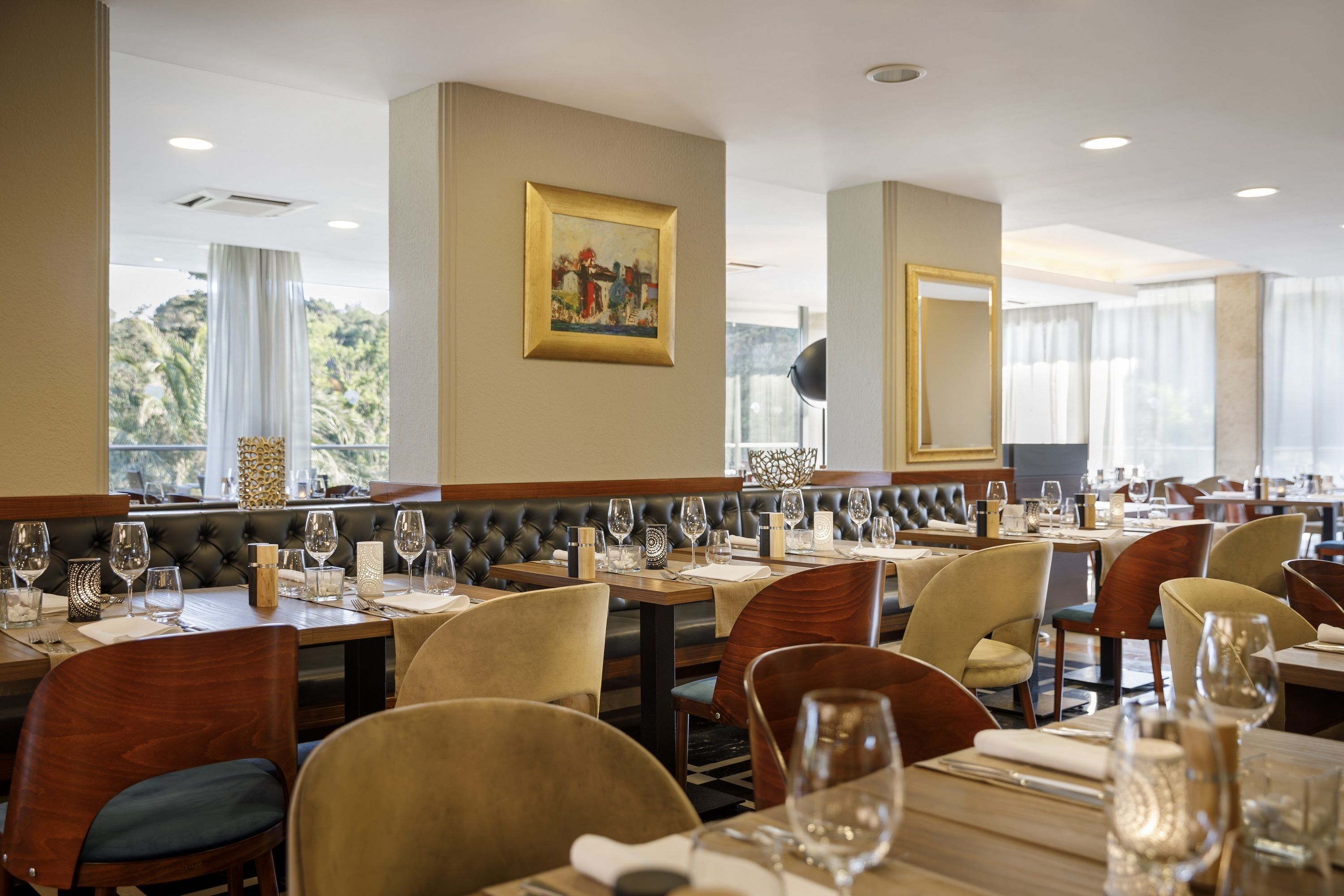 Un restaurant doté de nombreuses tables, de chaises confortables et d’une grande fenêtre donnant sur un paysage verdoyant.