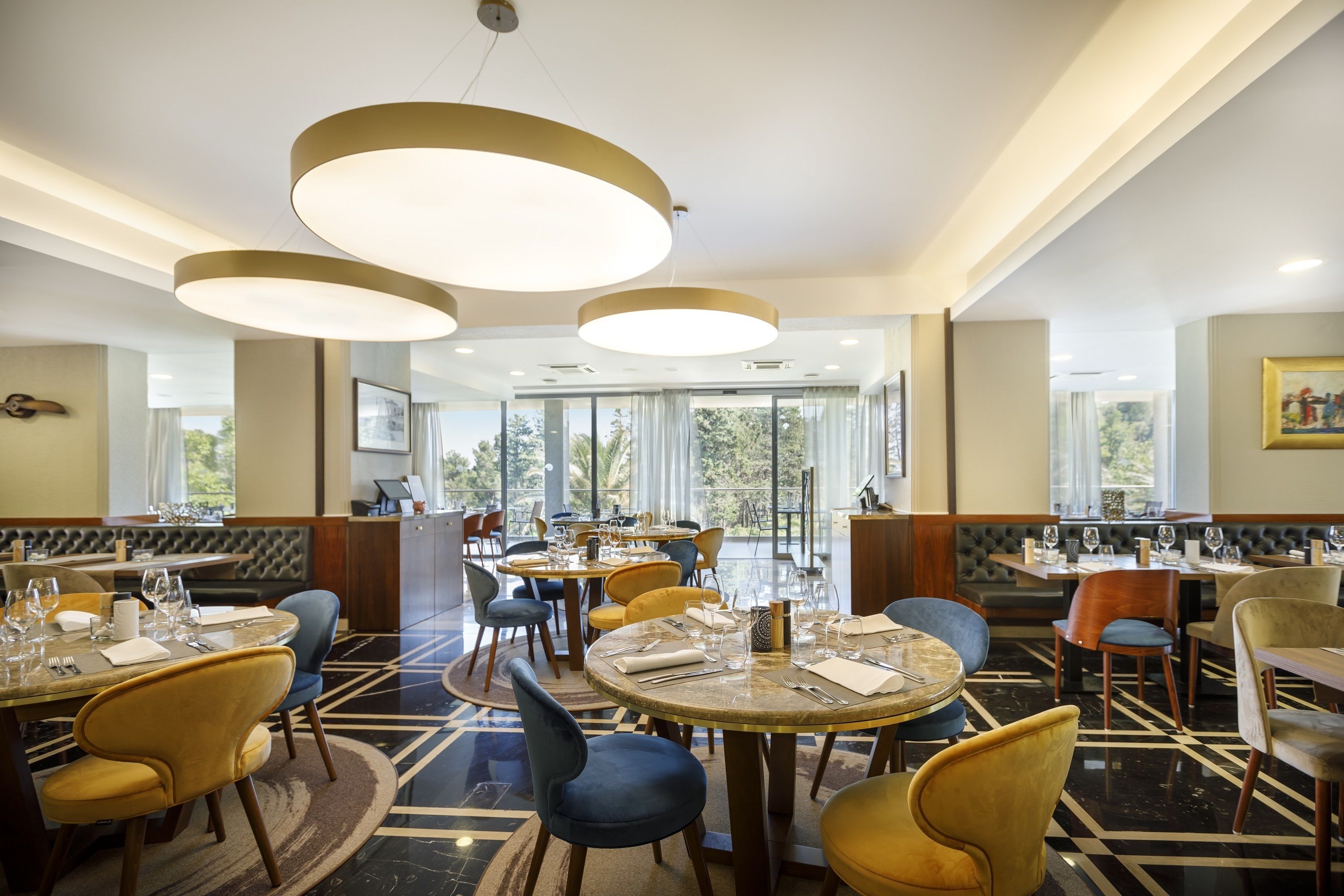 A restaurant with round tables, chairs, and pendant lighting.