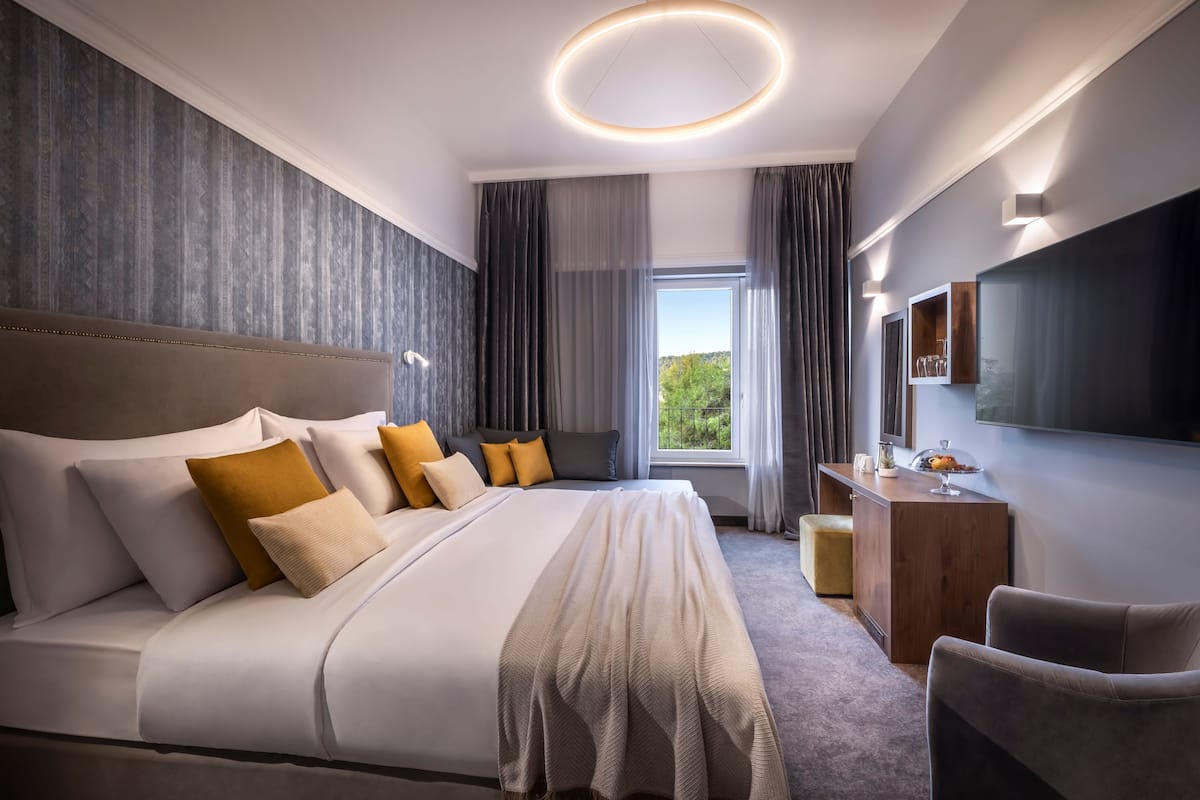 A modern hotel room with a large bed, a desk, and a TV.