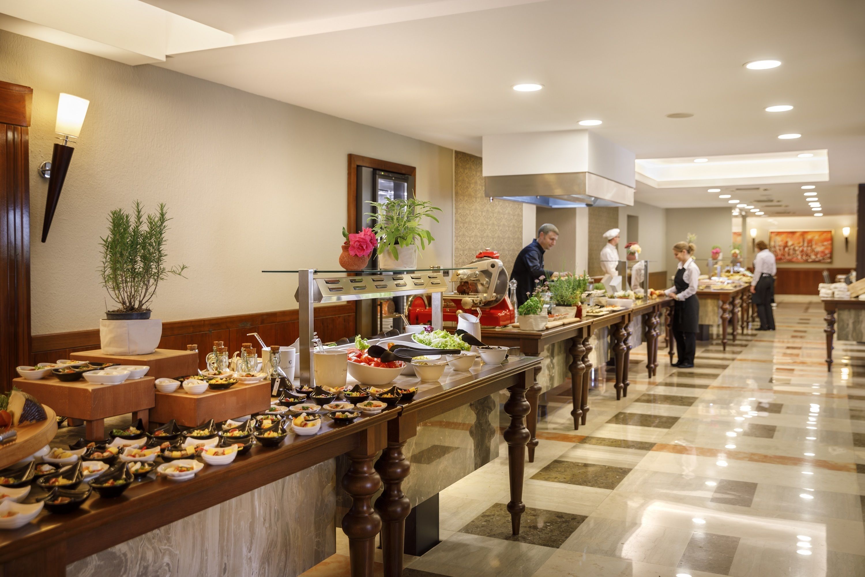 A buffet setup with various food items and staff serving.
