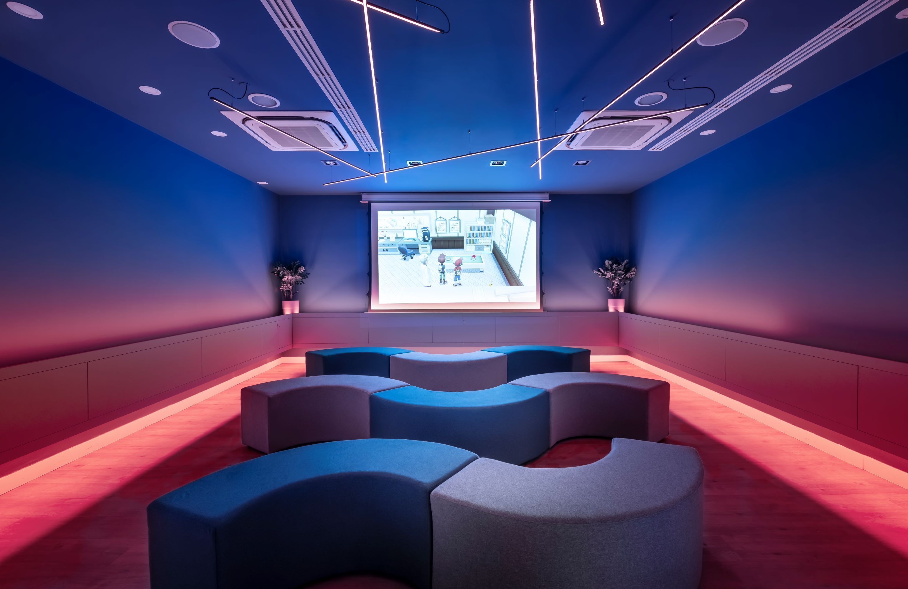 Una sala de cine moderna con una pantalla grande, asientos cómodos y un diseño de techo único.
