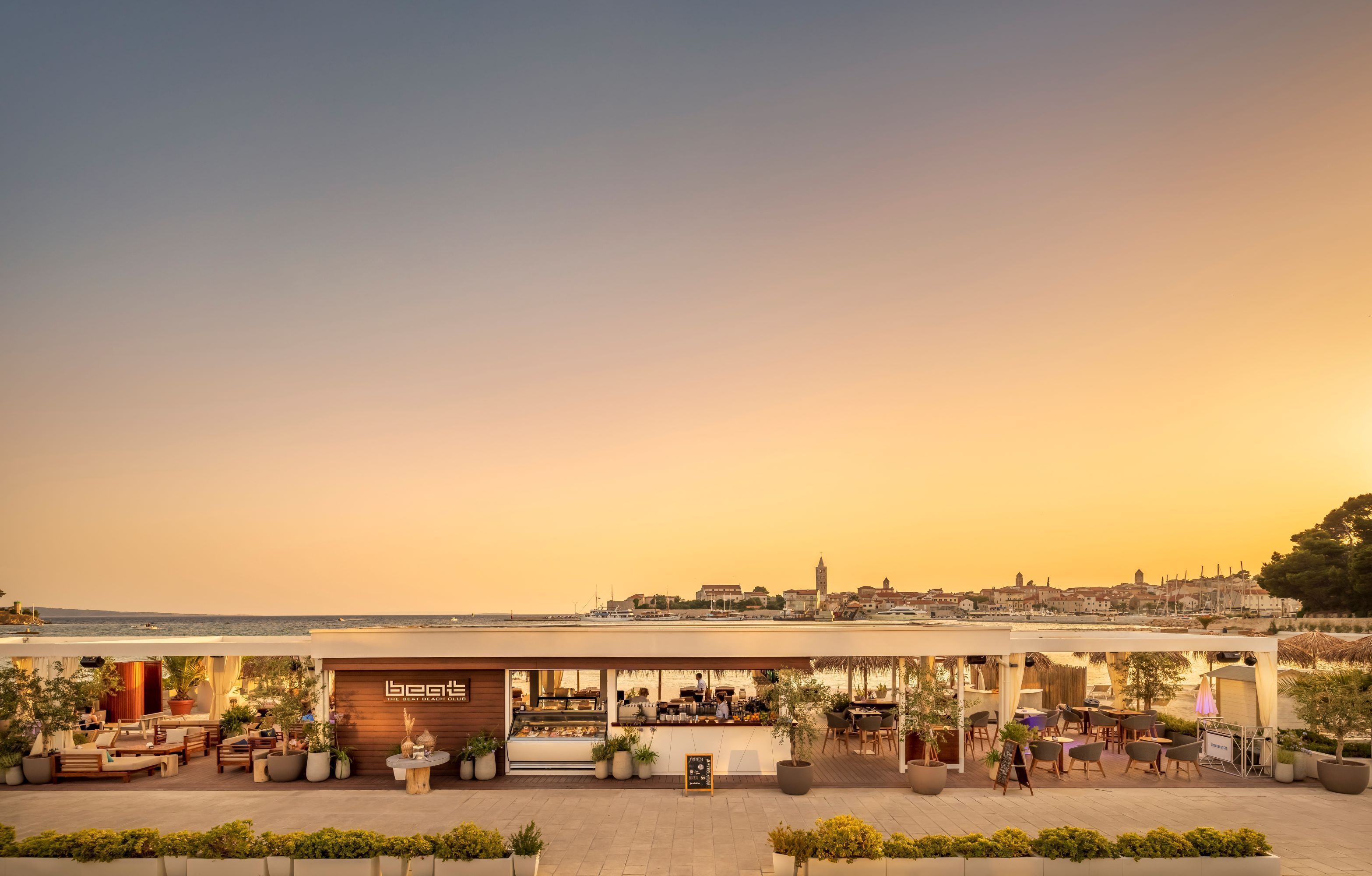 A waterfront restaurant with outdoor seating, a view of the city skyline, and a sign reading "beat's".