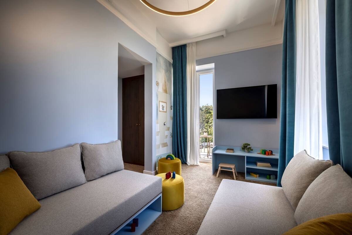 A modern living room with a sofa, ottoman, and a TV mounted on the wall.