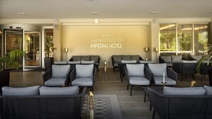 Een moderne hotel lobby met zitgedeeltes, een receptiebalie en een groot bord aan de muur.