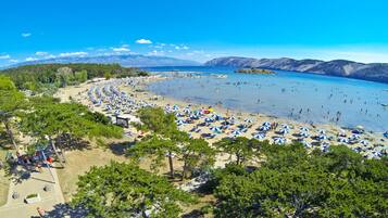Relax on a sandy beach surrounded by lush greenery and majestic mountains.