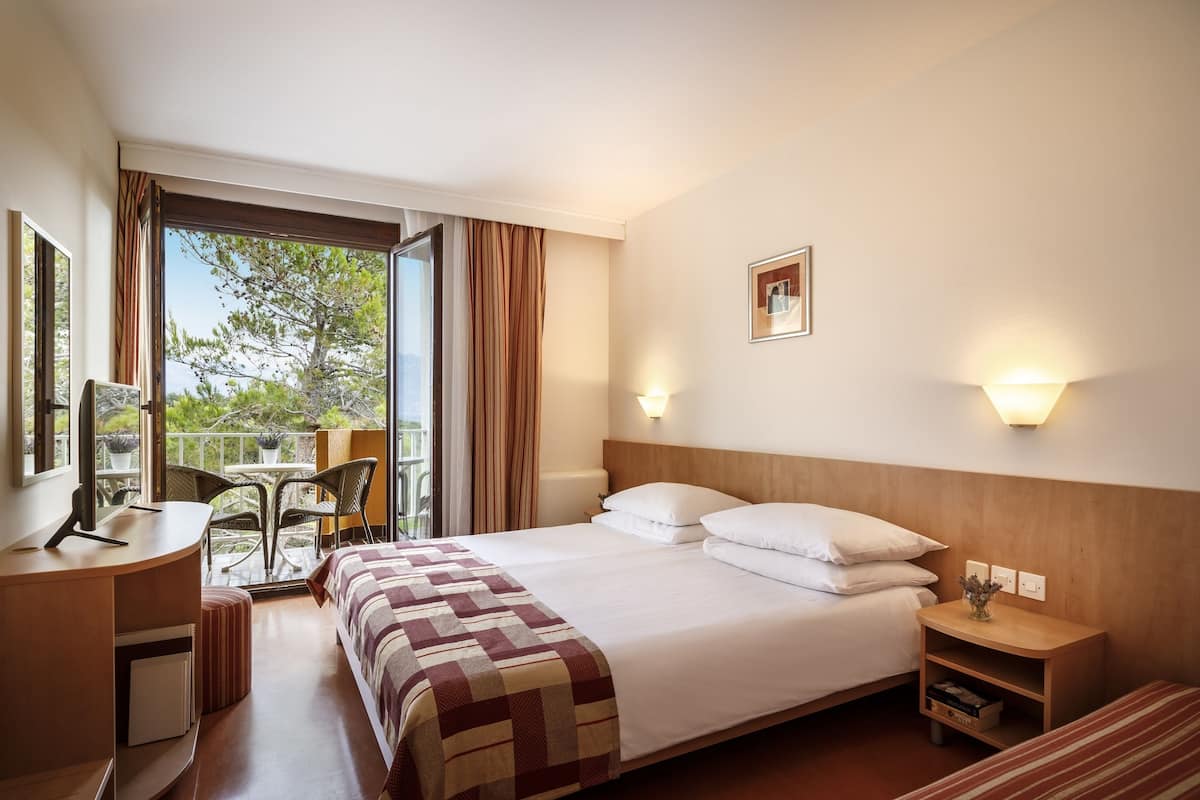 Une chambre d’hôtel avec un lit, une table de chevet, une lampe et une vue sur l’extérieur.