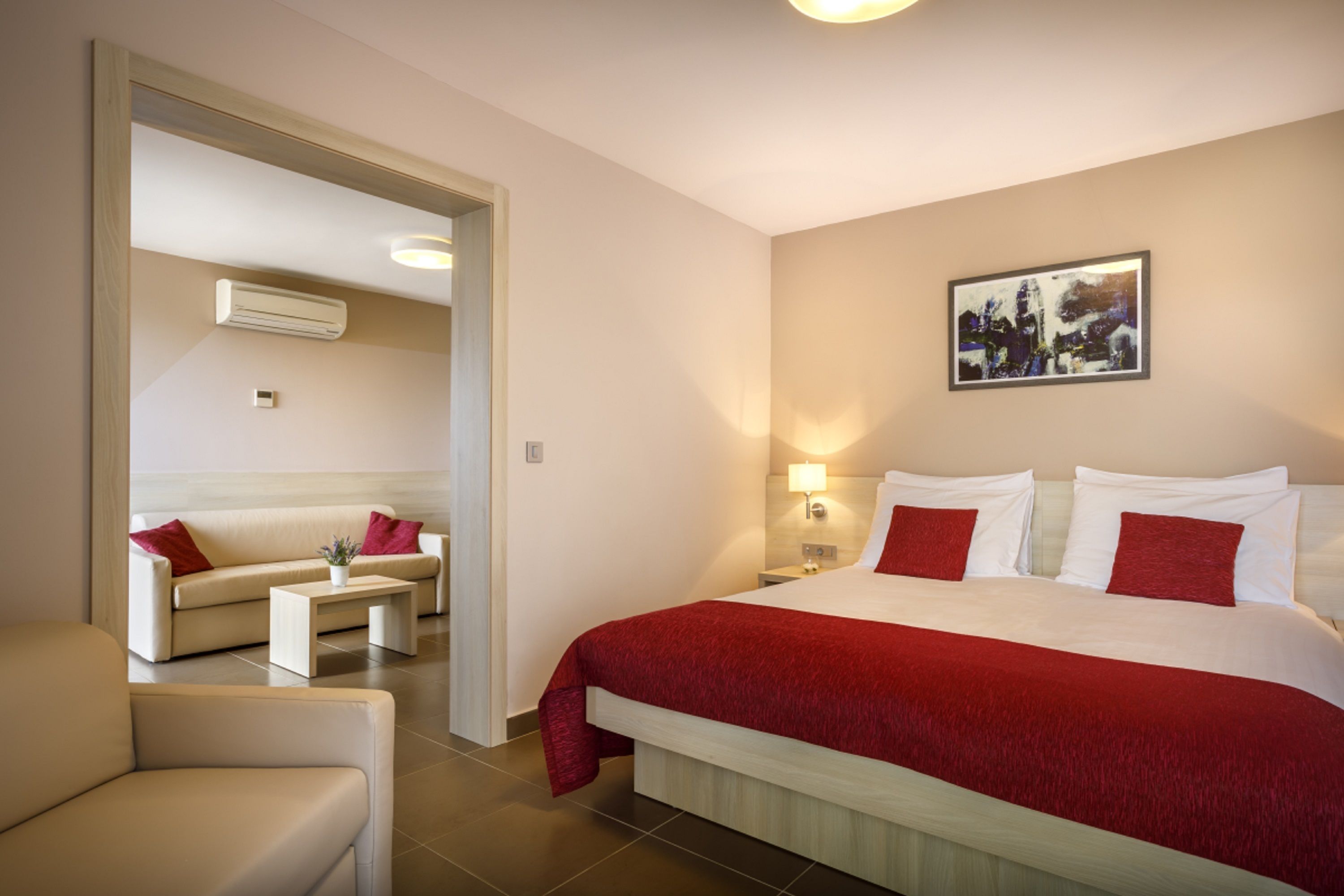 Een hotelkamer met een bed, een slaapbank, een bijzettafeltje en een schilderij aan de muur.