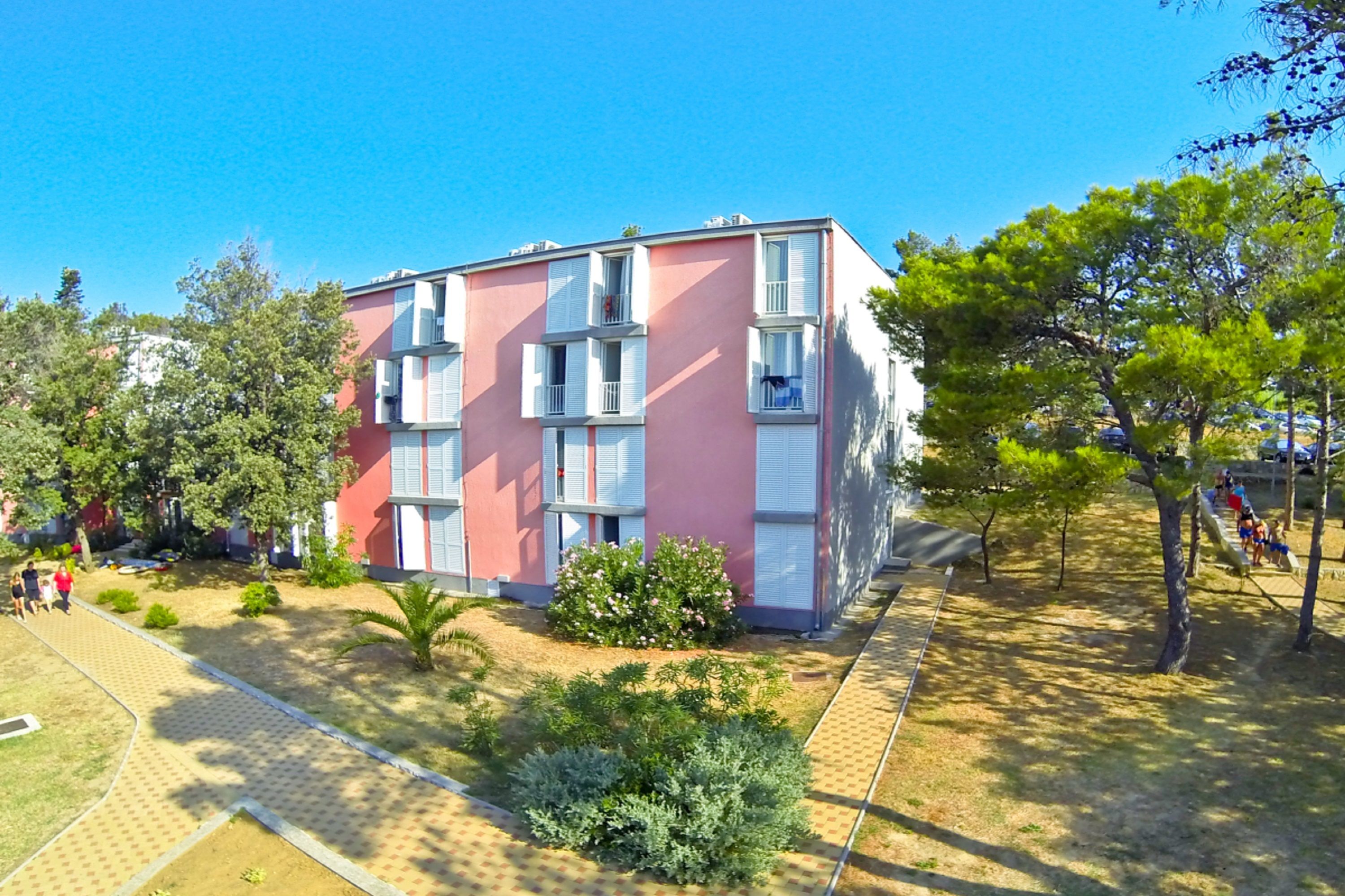 Un edificio a più piani con balconi e un'area giardino.