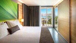 Hotelkamer met een bed, uitzicht op de bergen en een balkon met een tafel en stoelen.