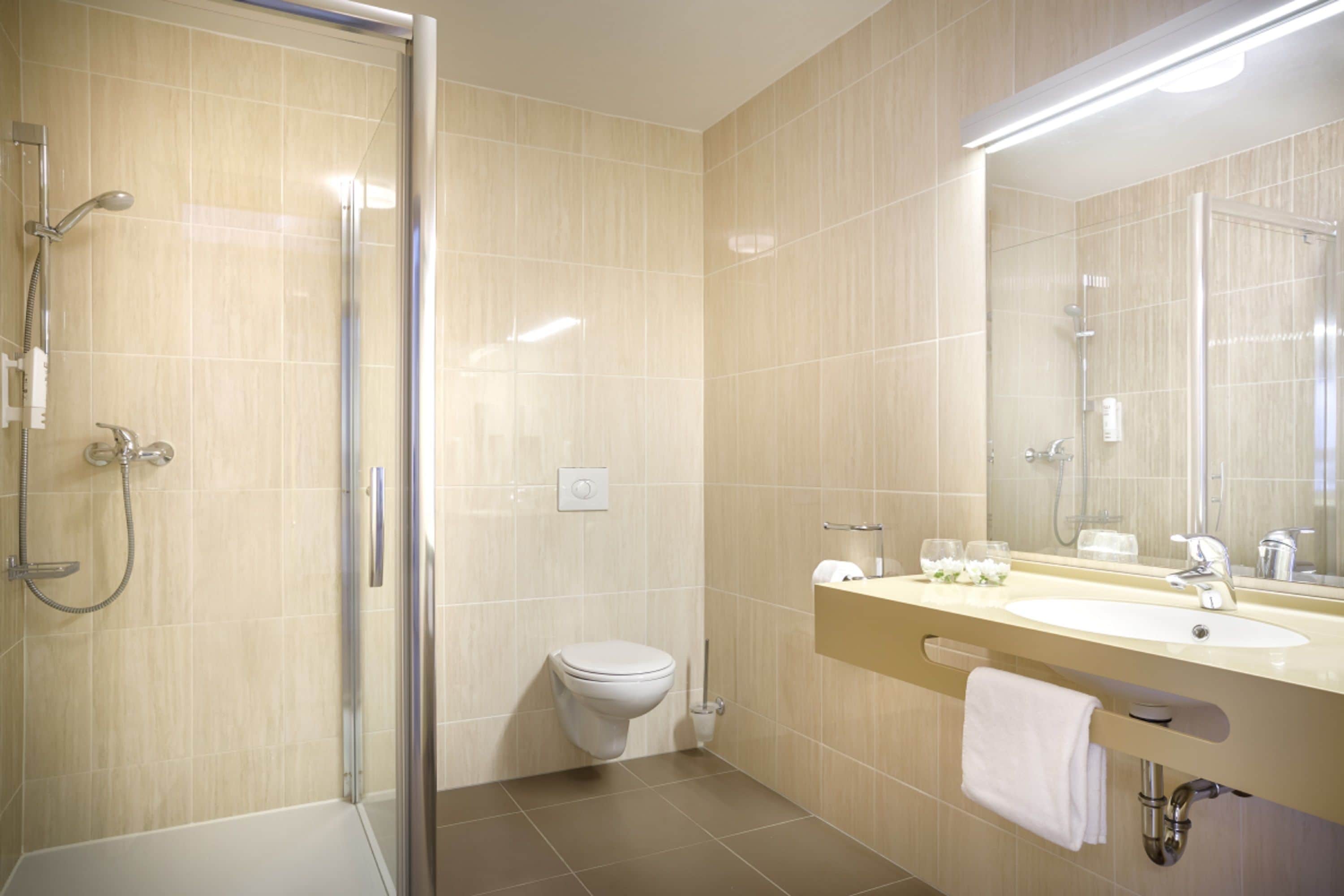 Un baño moderno con cabina de ducha de vidrio, inodoro y tocador con espejo.