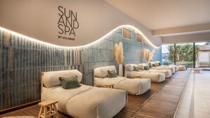 Un espacio de spa con varias zonas de descanso acolchadas, una pared con diseño vertical y un letrero que dice "SUN SPA BY VALAMAR".