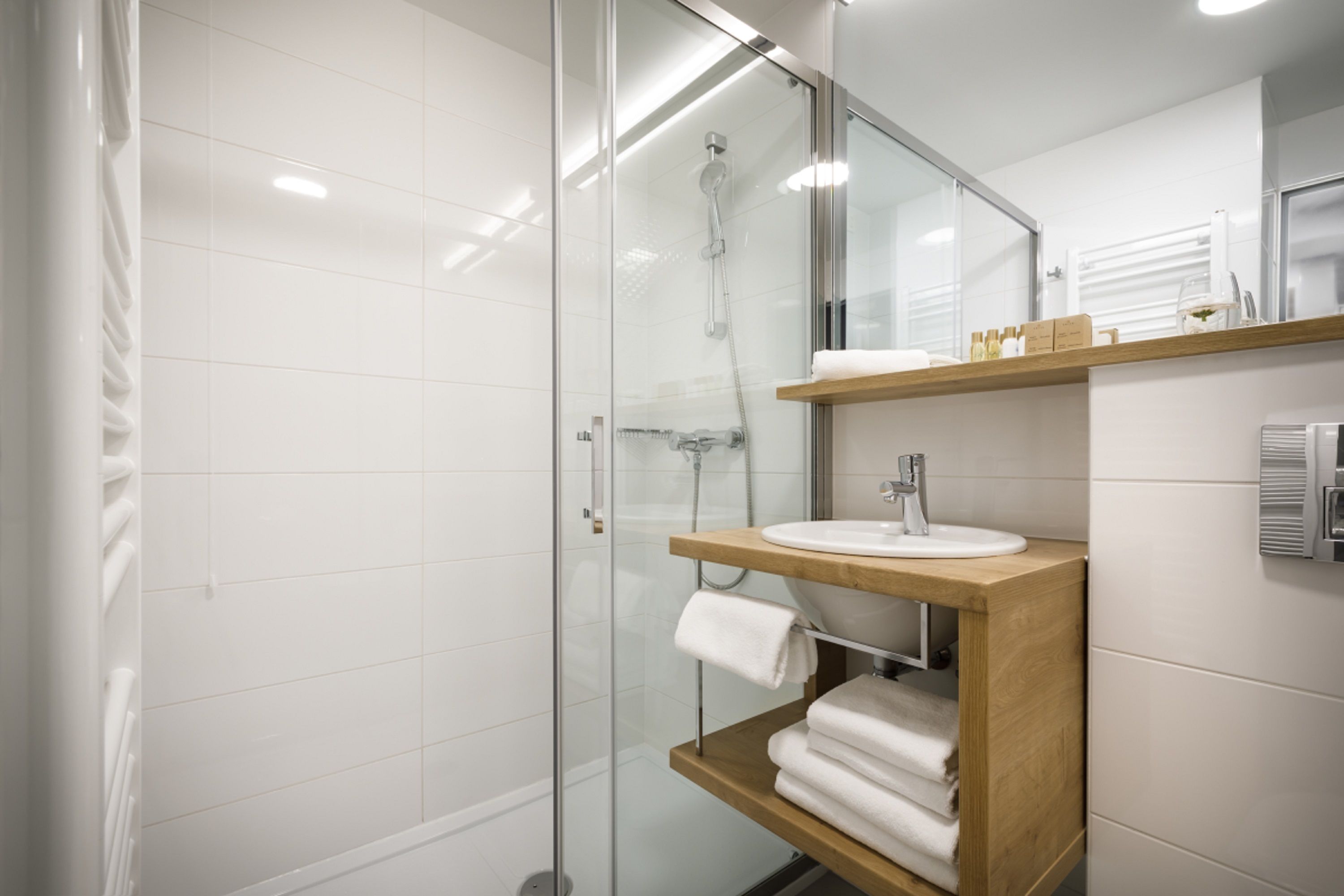 A modern bathroom with a glass-enclosed shower, a wooden vanity with a sink, and a mirror above it.