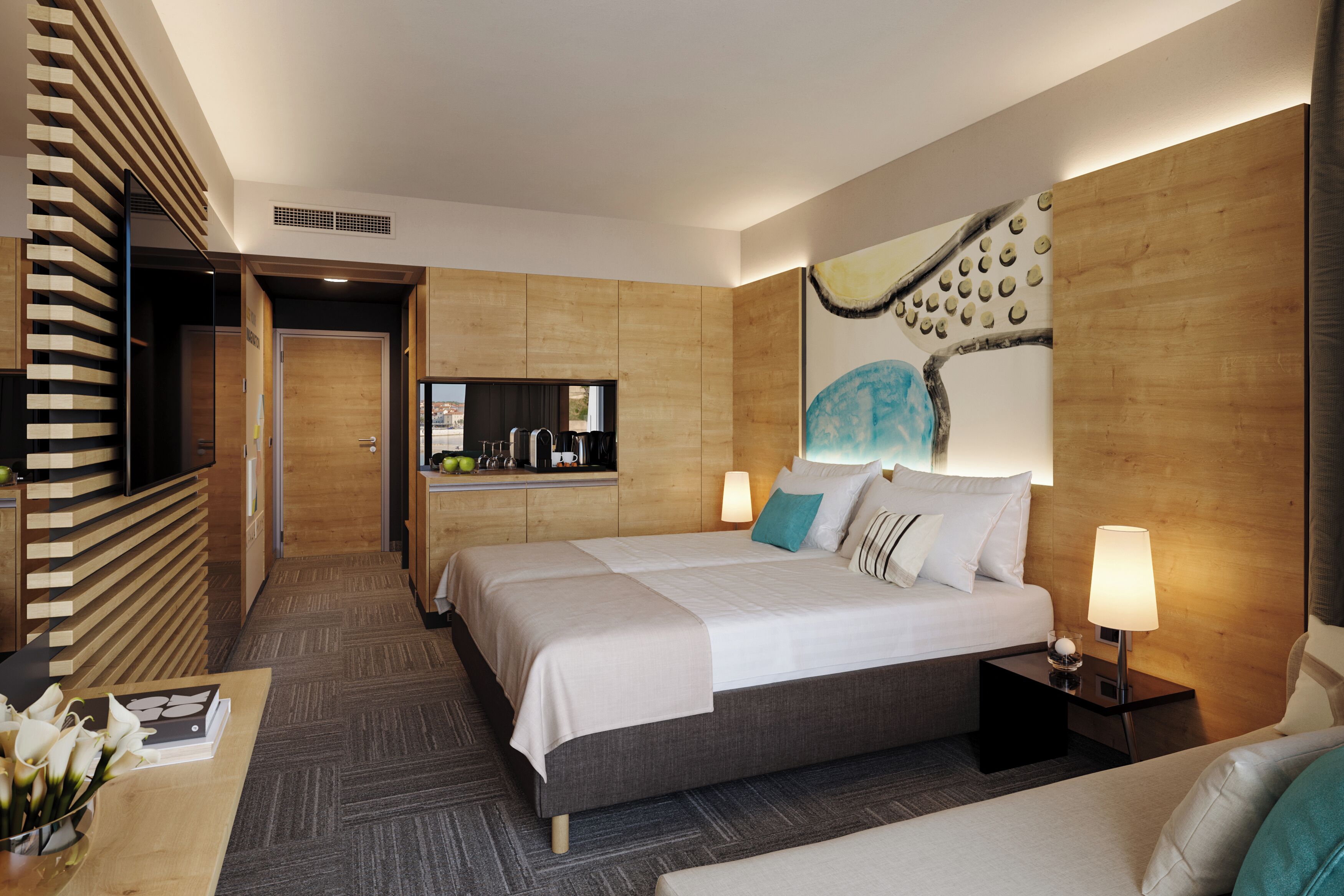 Habitación de hotel moderna con una cama grande, mesitas de noche, un escritorio y vistas a la ciudad.