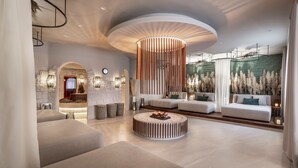 Un interior moderno con una zona de estar circular, una chimenea y un muro decorativo con elementos verticales.
