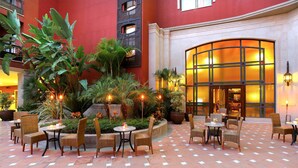 A courtyard with outdoor seating, potted plants, and a building entrance with a large glass door. - Barceló Marbella (Marbella)
