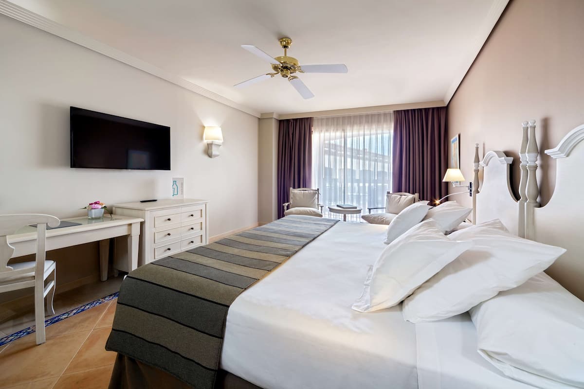 Una habitación de hotel con cama, escritorio, silla, televisor y vistas a la ciudad.