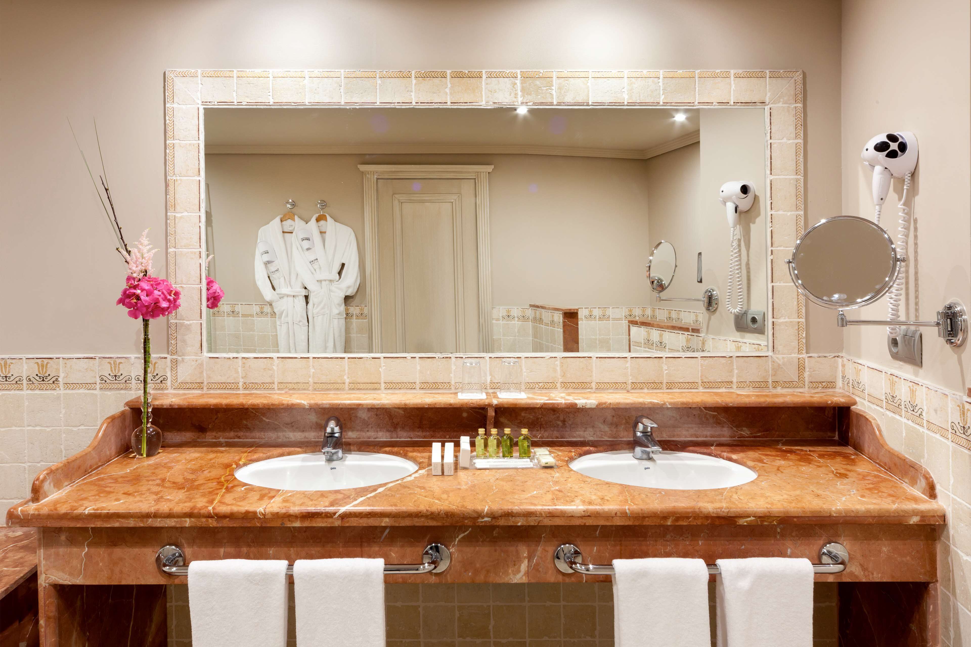A bathroom with two sinks, a large mirror, and a hairdryer mounted on the wall.
