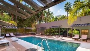 A modern outdoor pool area with lounge chairs, a pool with clear blue water, and surrounding greenery. - Barceló Marbella (Marbella)