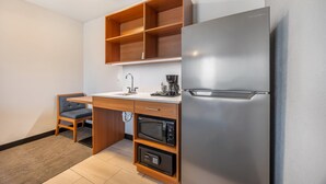 Una cocina compacta equipada con microondas, cafetera y refrigerador de acero inoxidable.