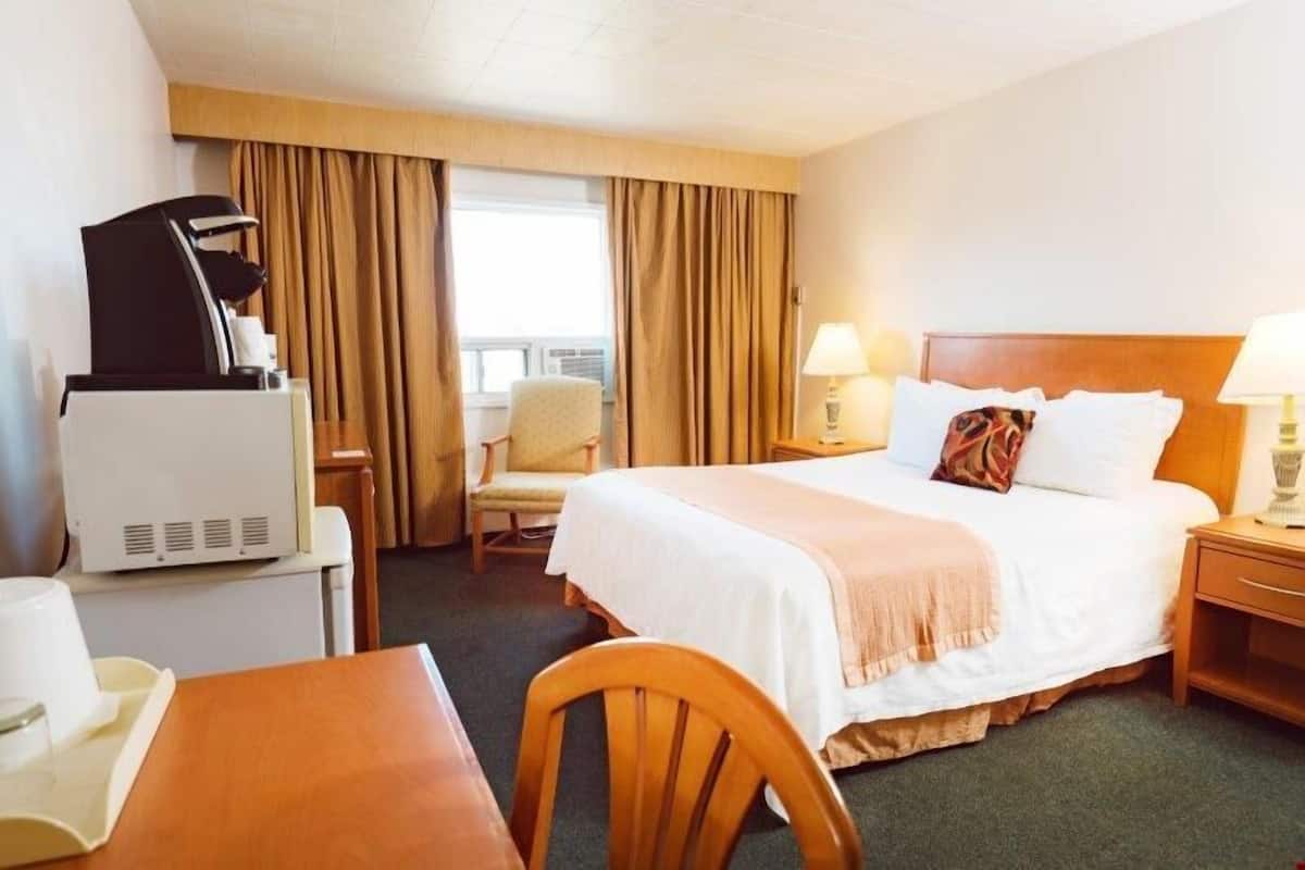 Una habitación de hotel con una cama, un escritorio, una silla, un televisor y una lámpara.