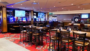 A casino area with multiple gaming machines, bar, and seating arrangements. - Rosslyn Inn and Suites (Edmonton)