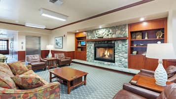 A spacious lobby with a stone fireplace, leather sofas, and a wooden coffee table.