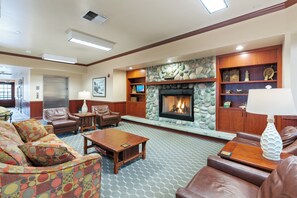 Eine geräumige Lobby mit einem Kamin aus Stein, Ledersofas und einem Holztisch.