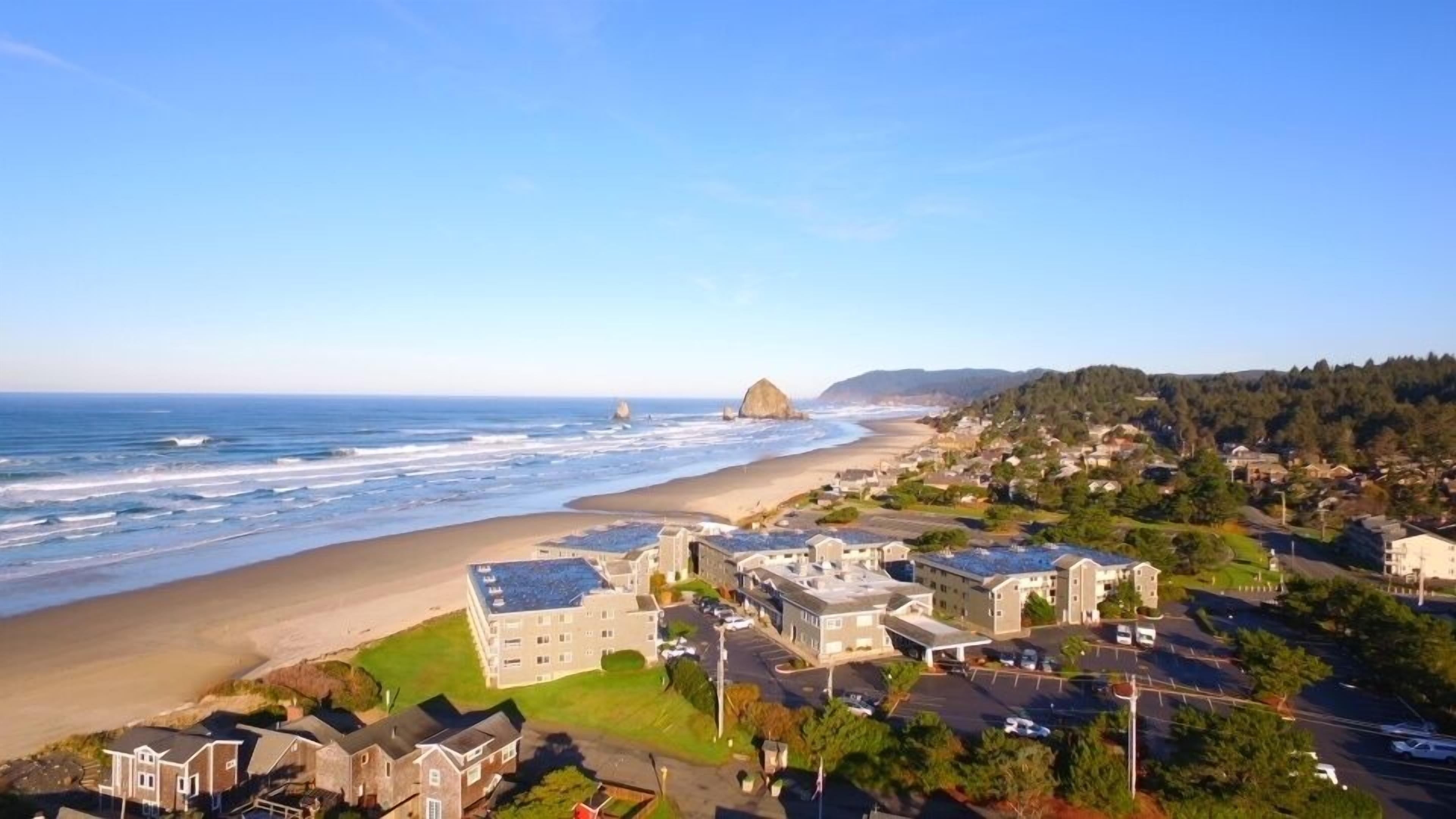 A coastal town with beachfront properties, a rocky outcrop, and a clear view of the ocean.