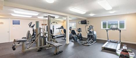 A gym with various exercise equipment, a treadmill, and a weight bench.