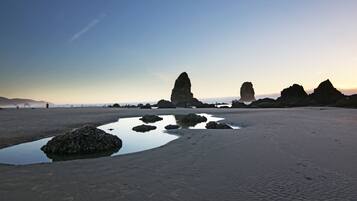 A beach with large rock formations and a calm water body.