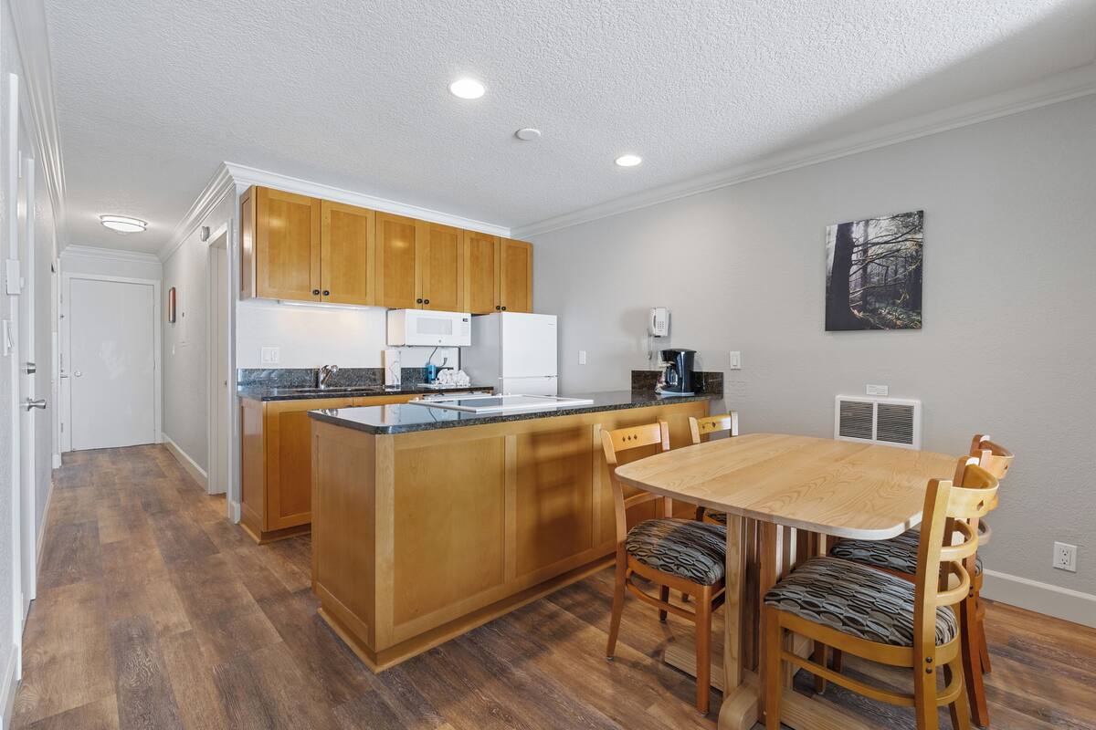 A modern kitchen with wooden cabinets, a central island, and a dining area with a wooden table and chairs.