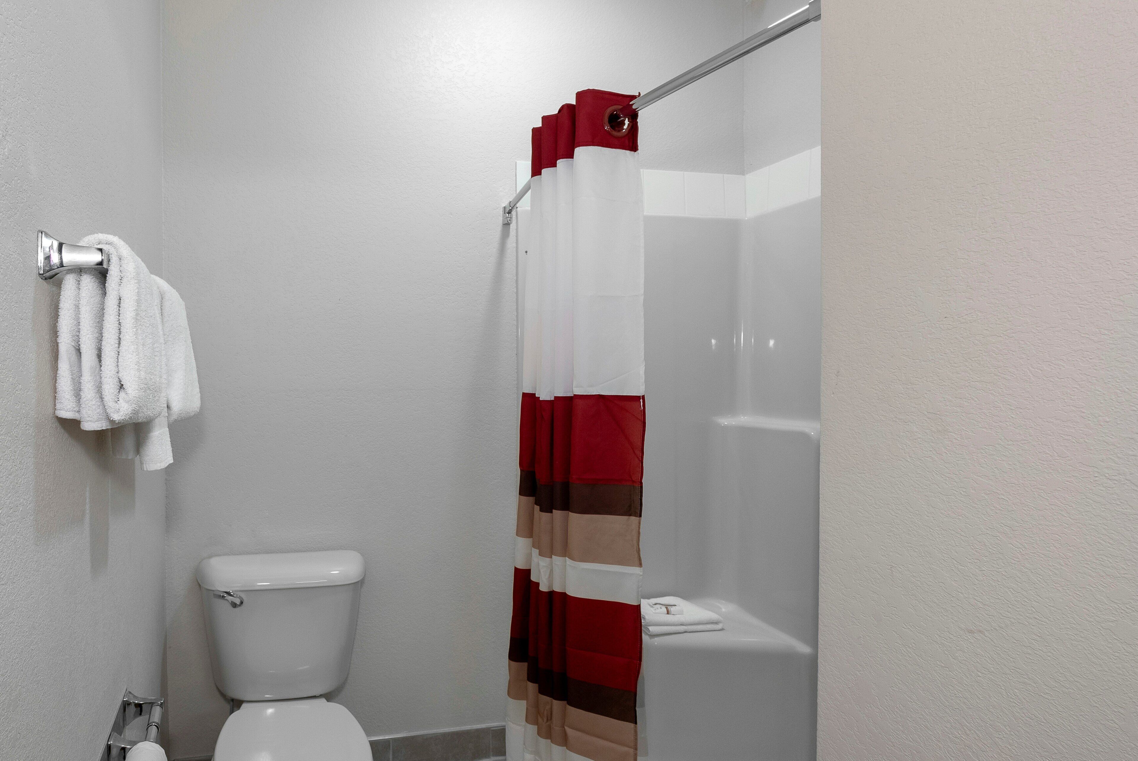 Un baño con inodoro, cortina de ducha y barra para toallas.