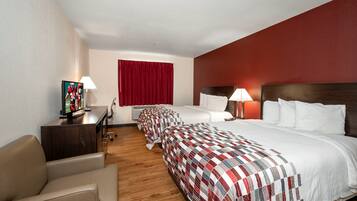 Une chambre d’hôtel avec deux lits, un bureau avec un ordinateur, une chaise et un téléviseur.