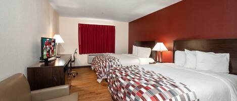 A hotel room with two beds, a desk with a computer, a chair, and a TV.