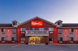 Un Red Roof Inn con un llamativo letrero rojo, un balcón y fachada de ladrillo.