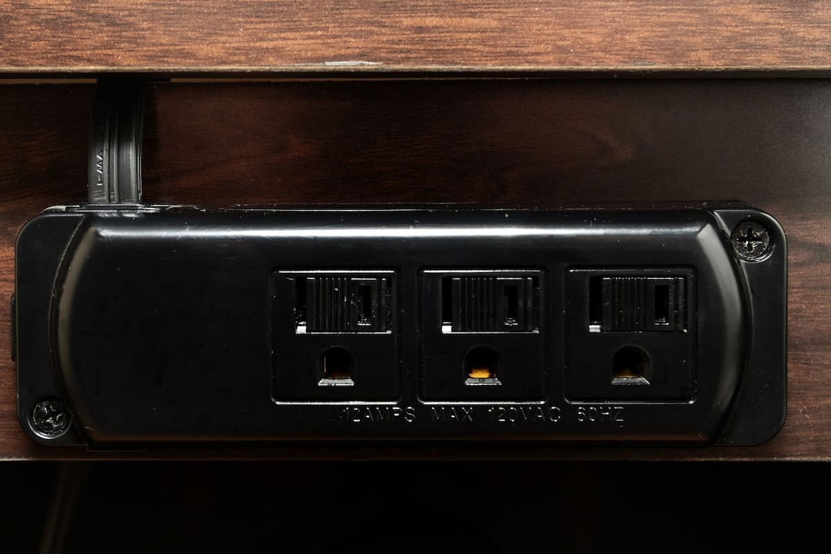 A black electrical outlet with three sockets, a screw, and a label reading 'MAX 20VAC 3PH'.