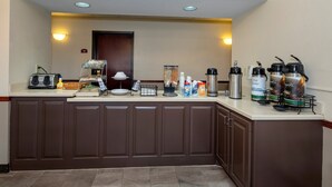 Quarto de hotel com cozinha compacta, incluindo cafeteira, chaleira e diversos temperos.