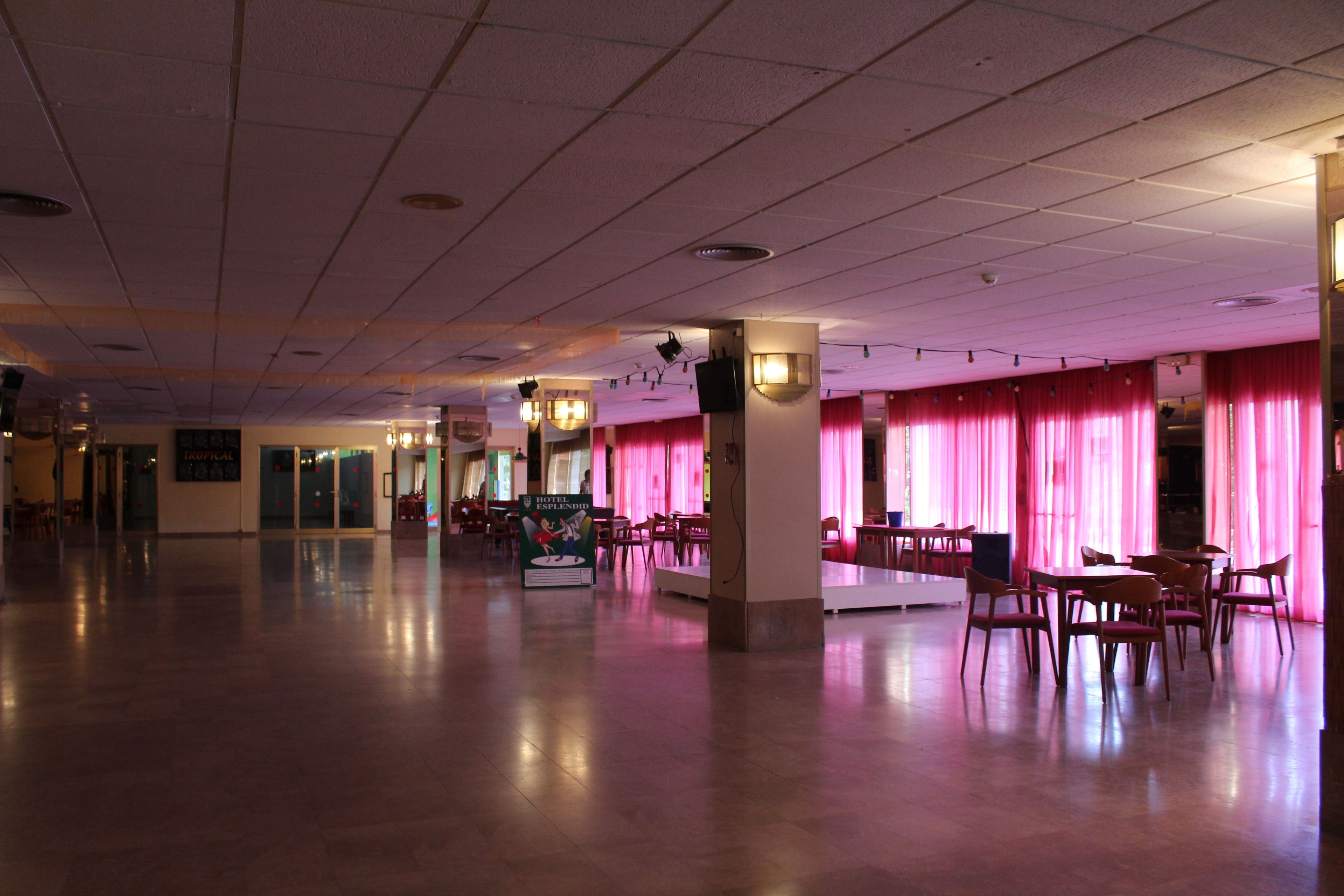 A spacious hotel lobby with a high ceiling, multiple seating areas, and a sign indicating a restaurant.
