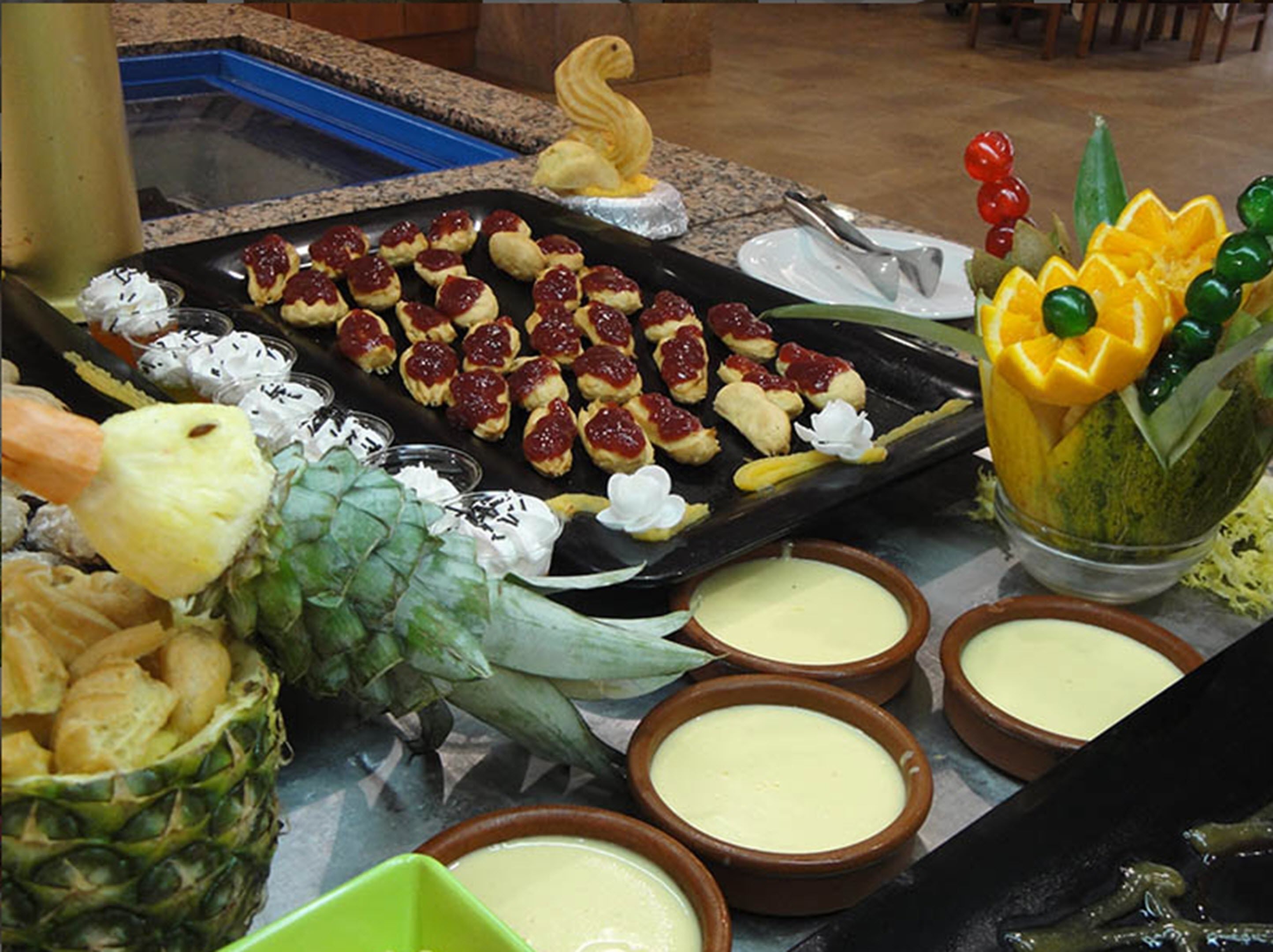 A buffet with various food items including pastries, fruits, and dips.