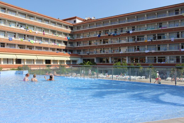 Un hôtel doté de nombreux balcons, d’une piscine et d’un espace couvert avec des chaises longues.