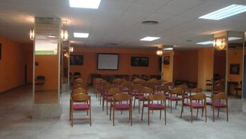 Un salón de conferencias con filas de sillas de madera y una pizarra.