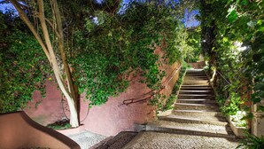A stone staircase with a brick-tiled path leading up to a pink wall. - York House (Lisbon)