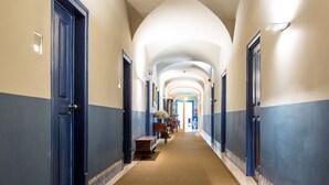 A hotel corridor with a series of doors, a bench, and a mirror on the wall. - York House (Lisbon)