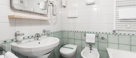 A bathroom with a sink, toilet, bidet, and a mirror.