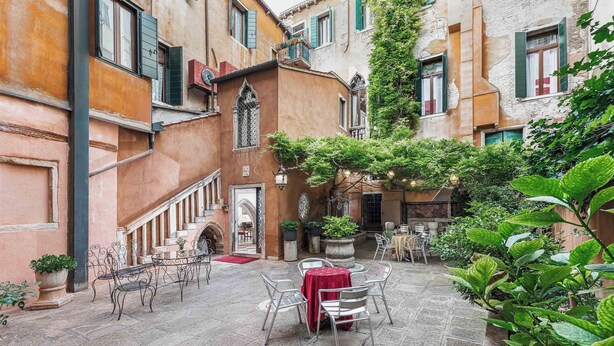 A courtyard with outdoor seating, stone flooring, and surrounding buildings with traditional architecture. - Hotel San Moisè (Venice)