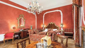 A luxurious room with a red wall, ornate furniture, a chandelier, and a bed with a canopy. - Hotel San Moisè (Venice)