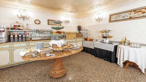 A breakfast buffet with various food items and beverages, a chandelier, and a decorative ceiling. - Hotel San Moisè (Venice)