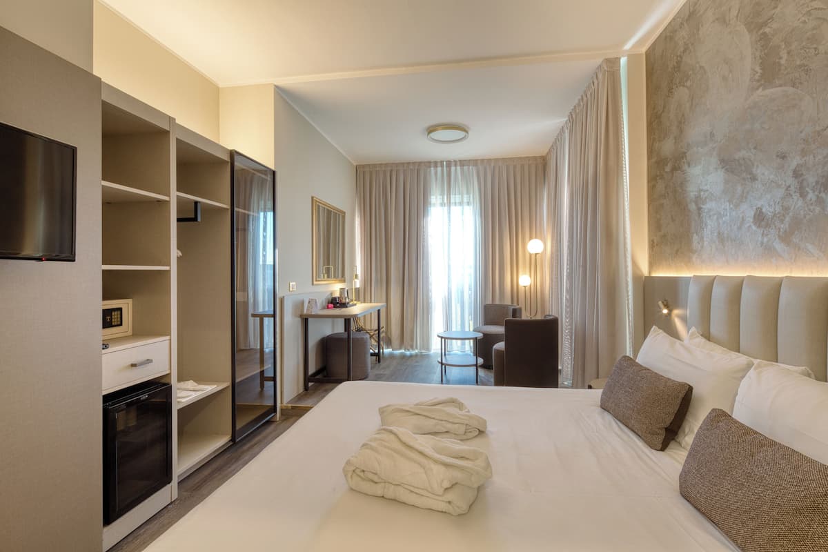A hotel room with a bed, a desk, a chair, a TV, and a wardrobe.