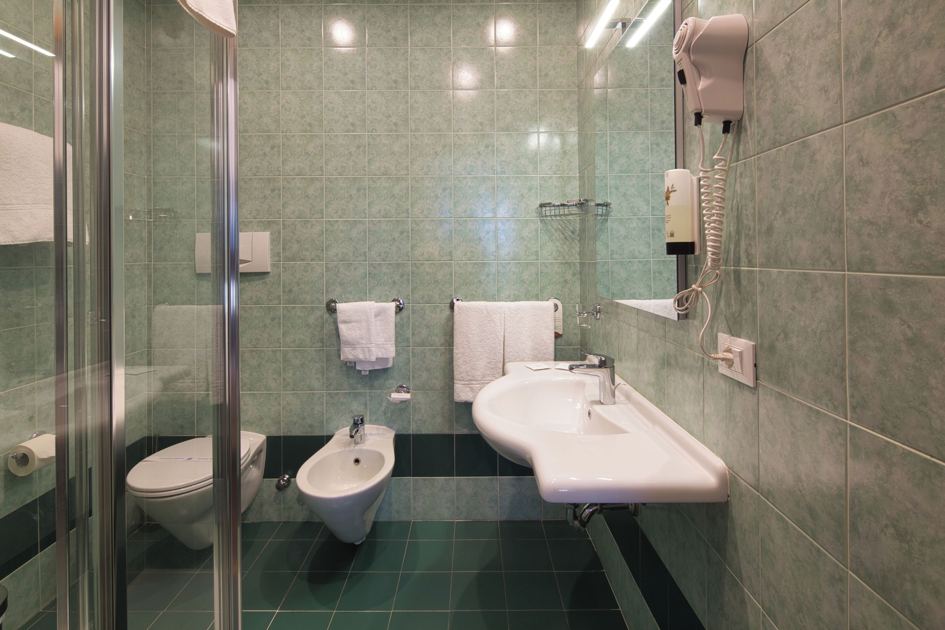 Een badkamer met een hygiëneschuiver, toilet en wastafel.